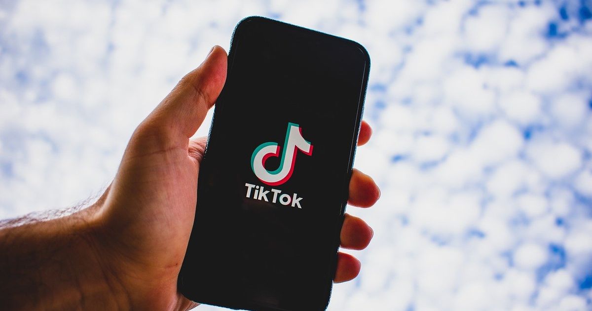 How to see videos you reposted on TikTok man holding phone