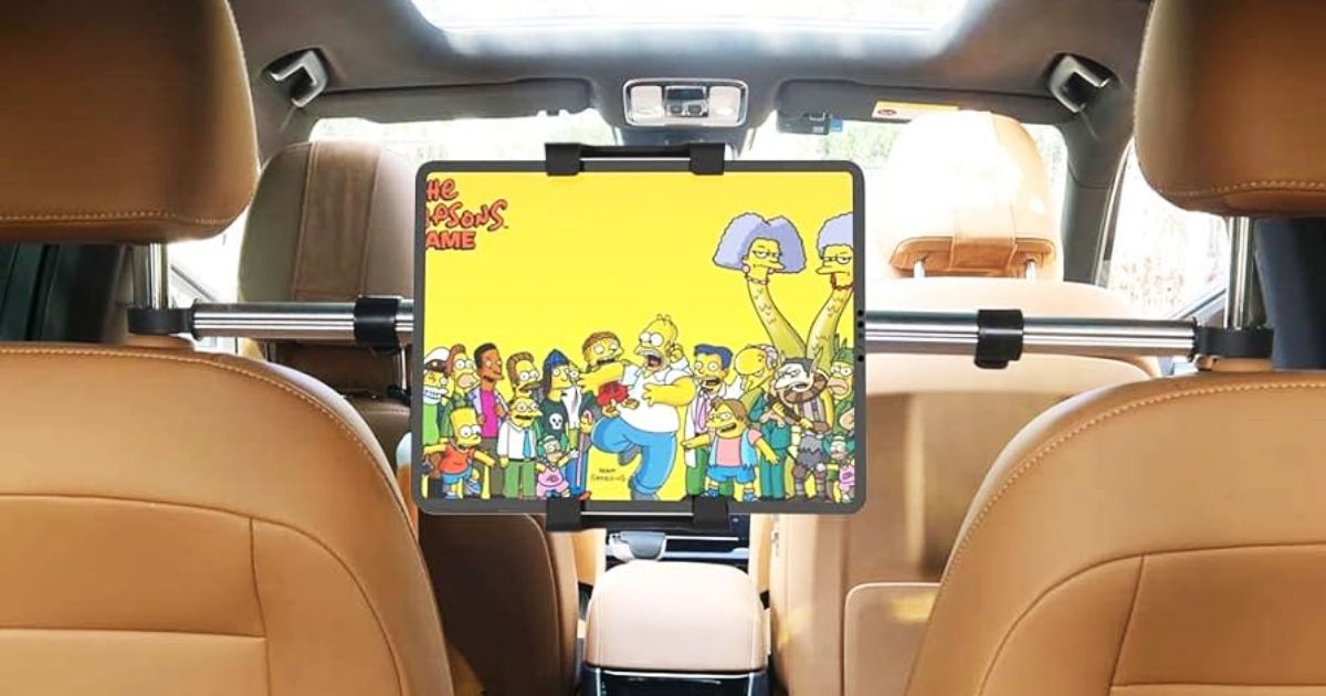 A tablet with Simpsons on the display mounted between two brown leather car seats.