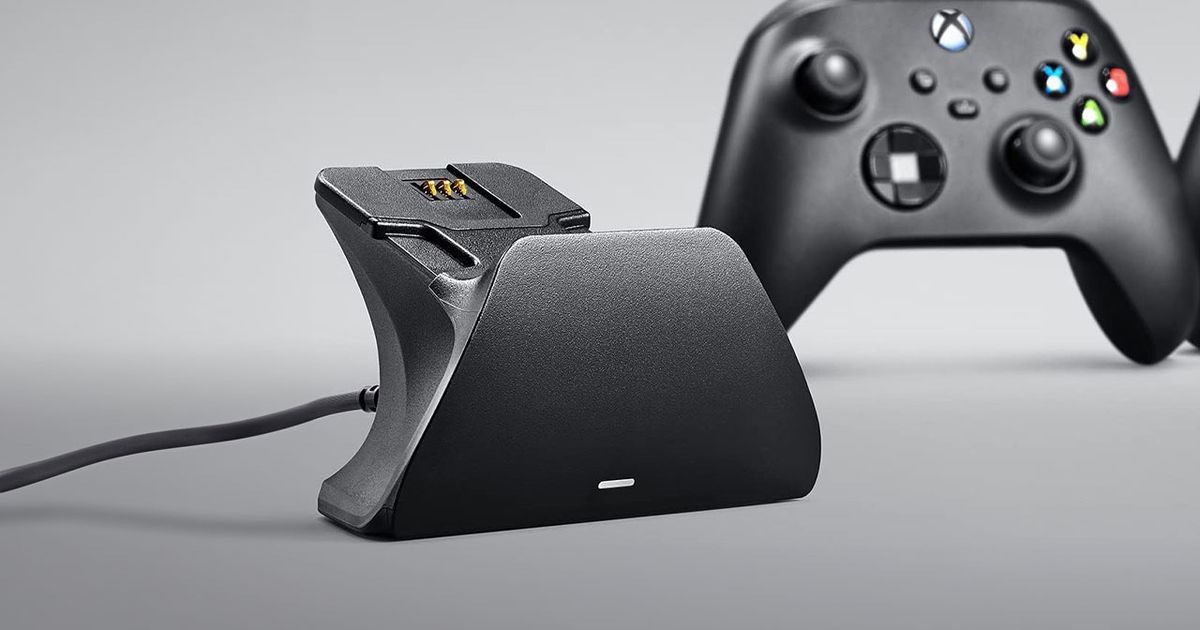 A black, wired charging stand sat ahead of a black Xbox controller.