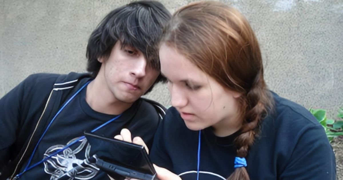 A 2008 image of two friends, a black-haired male and a brunette female, playing the Nintendo DS outside 