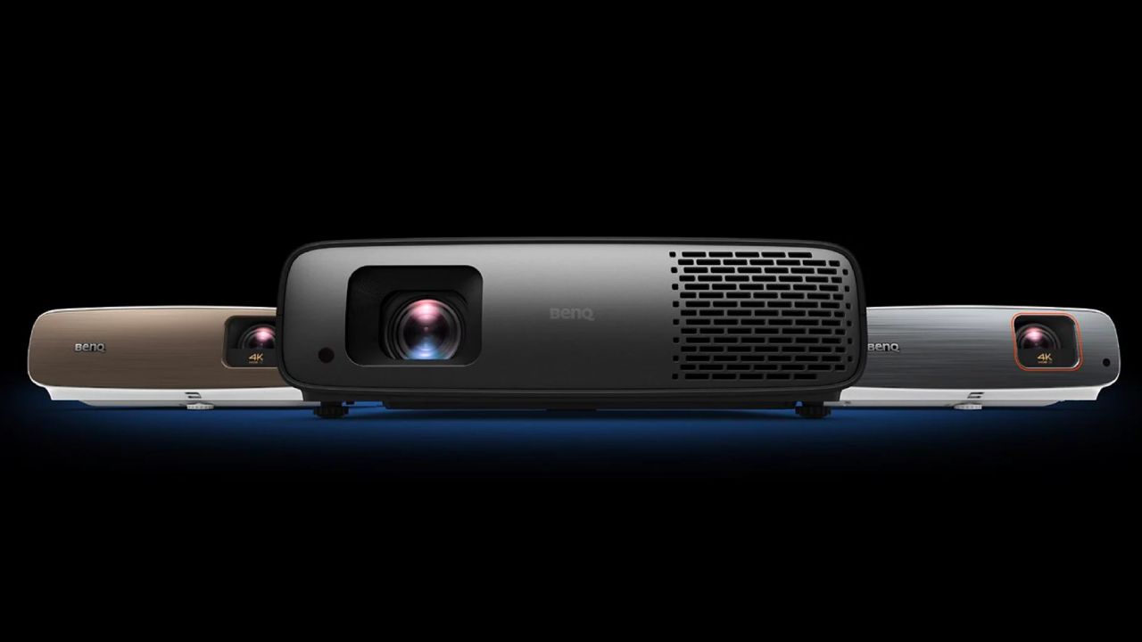 A black projector next to a brown and lighter grey and white version in a black room.