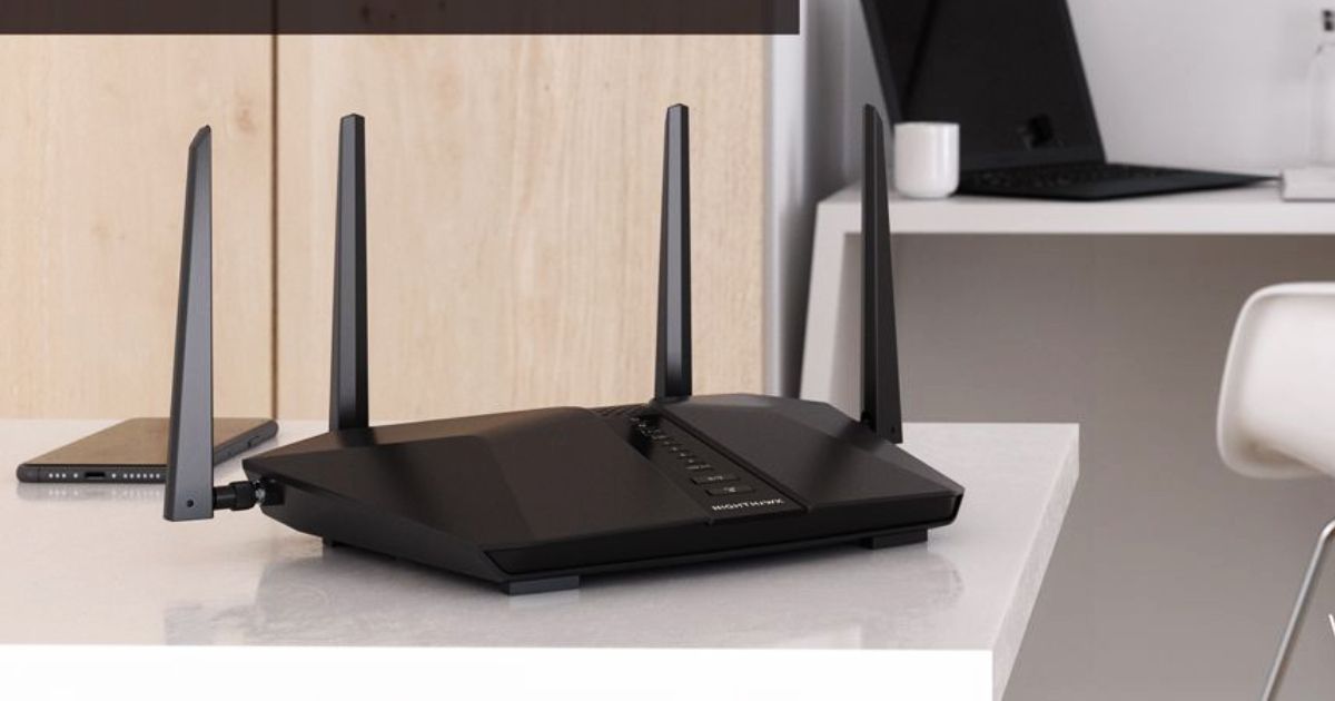 A black WiFi router with four antennae sat on a white table.