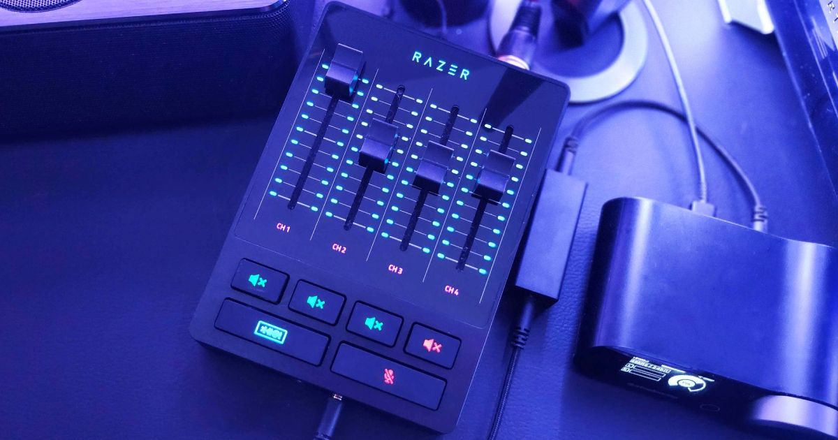 A black audio mixer bathed in blue light, featuring light blue and red lights on it.