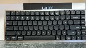 Lofree Flow keyboard in black in front of the box and on a marble countertop