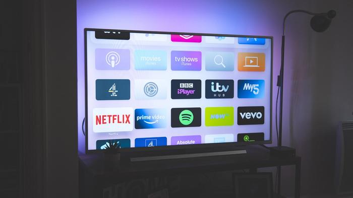 Image of a TV with blue and purple backlighting featuring multiple apps on the display, including Netflix, BBC iPlayer, etc.