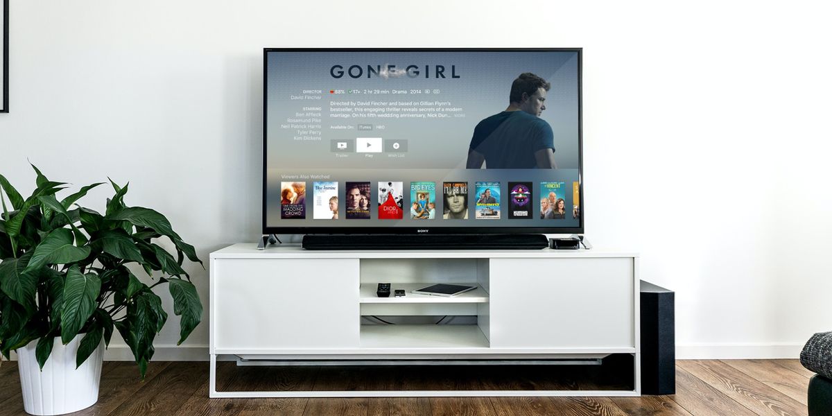 Image of a black TV on a white stand featuring a choice of films on the display, with Gone Girl selected.