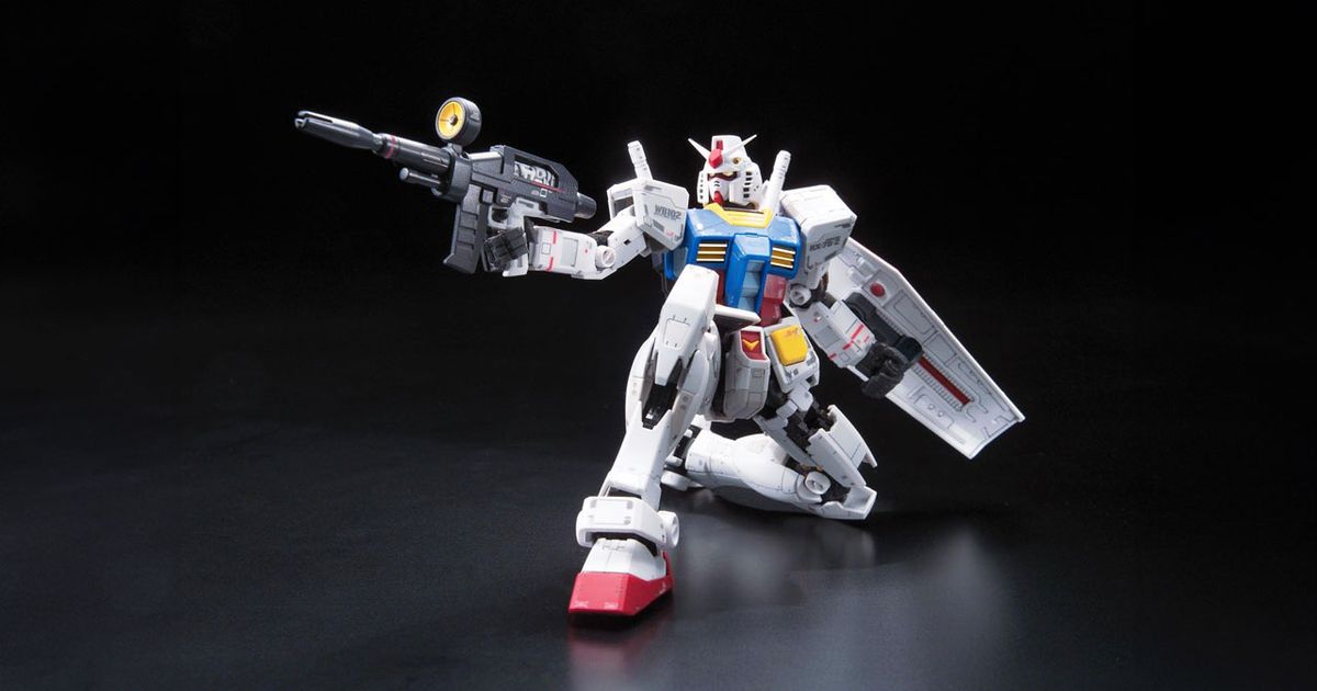 A white, blue, yellow, and red Gundam model holding a weapon in one hand and a shield in the other