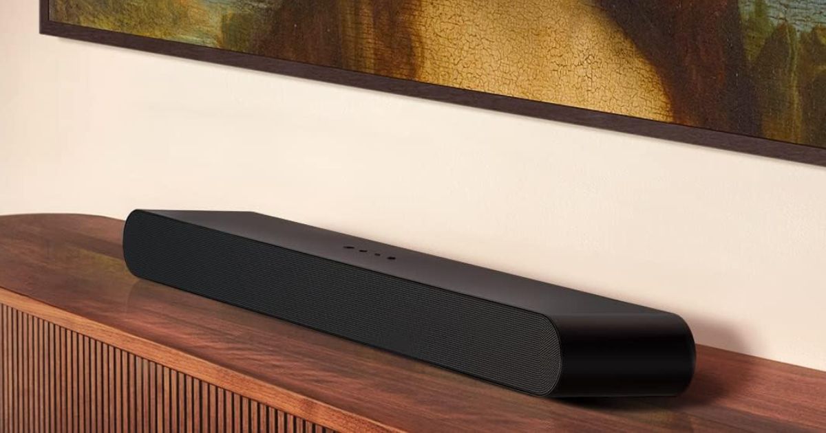 A long black rectuangular soundbar with curved ends sat on a wooden stand.