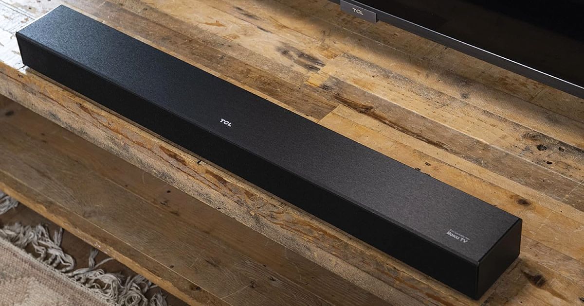 A black, rectangular soundbar sat on a wooden stand.