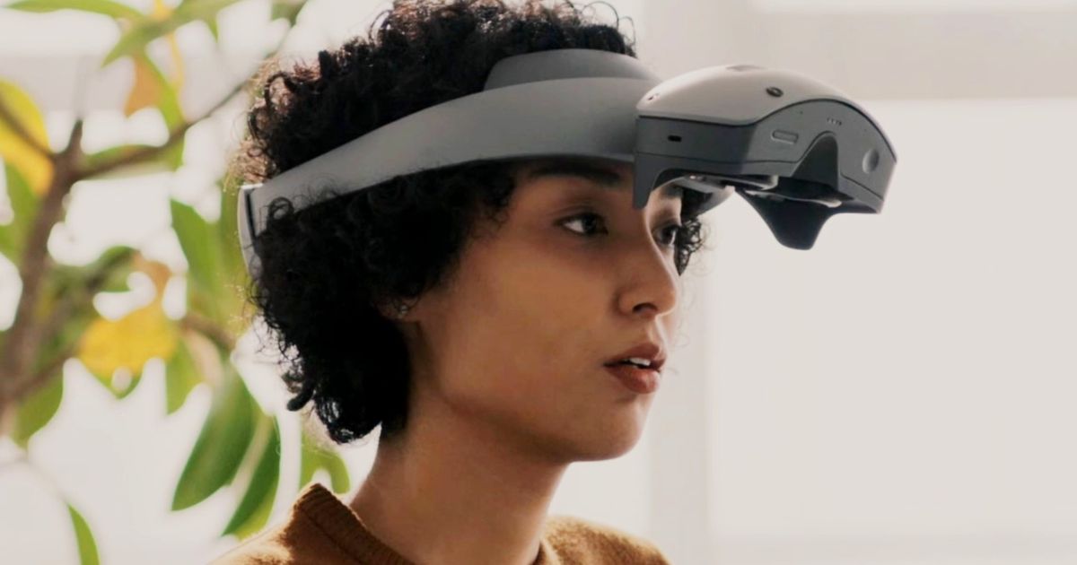 A woman with dark curly hair wearing the Sony MR headset with the top flipped up 