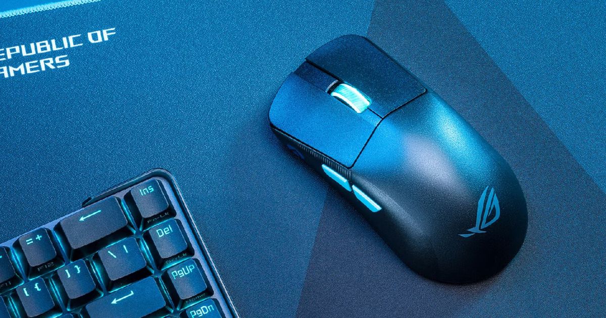Image of a black wireless mouse with a grey scroll wheel on a Republic of Gamers mat and next to a keyboard in a blue lit room.