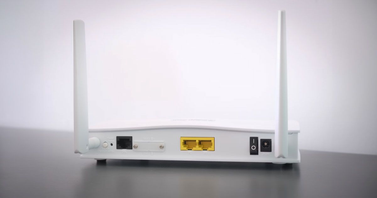 A white Wi-Fi router shot from the back featuring two antennas pointing upwards.