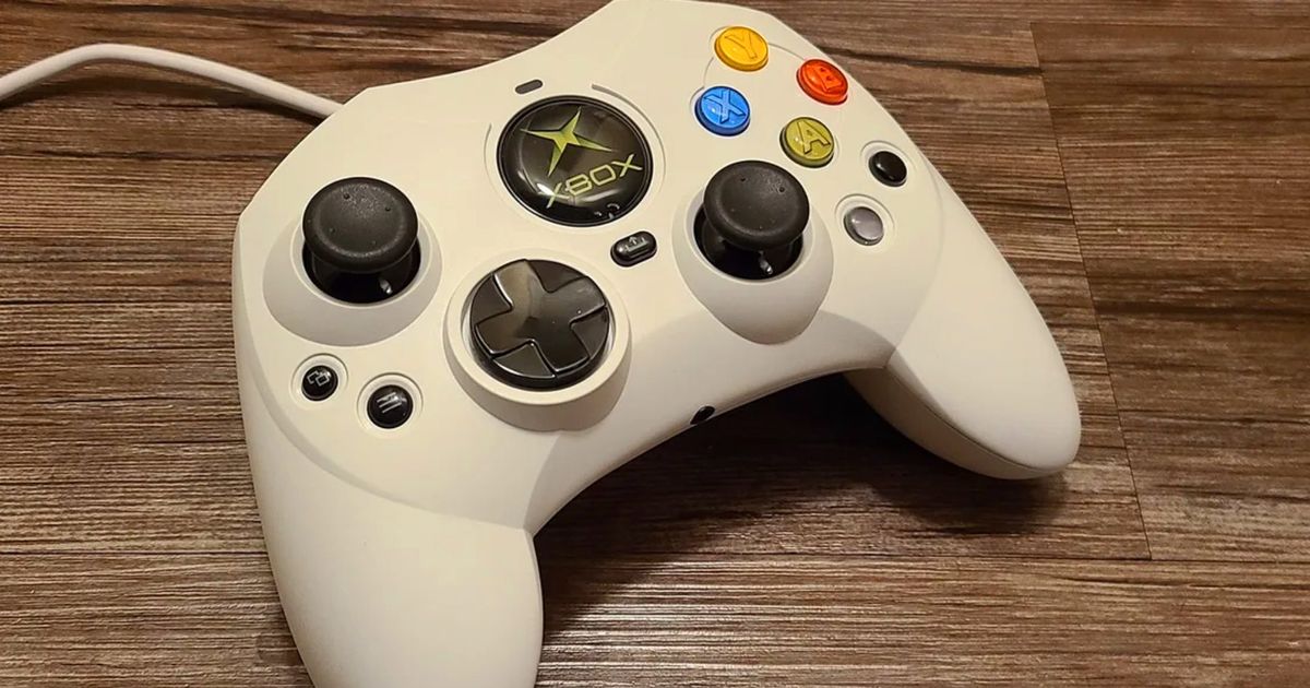 The Hyperkin Duchess Original Xbox S controller in a white skin on a wooden table 