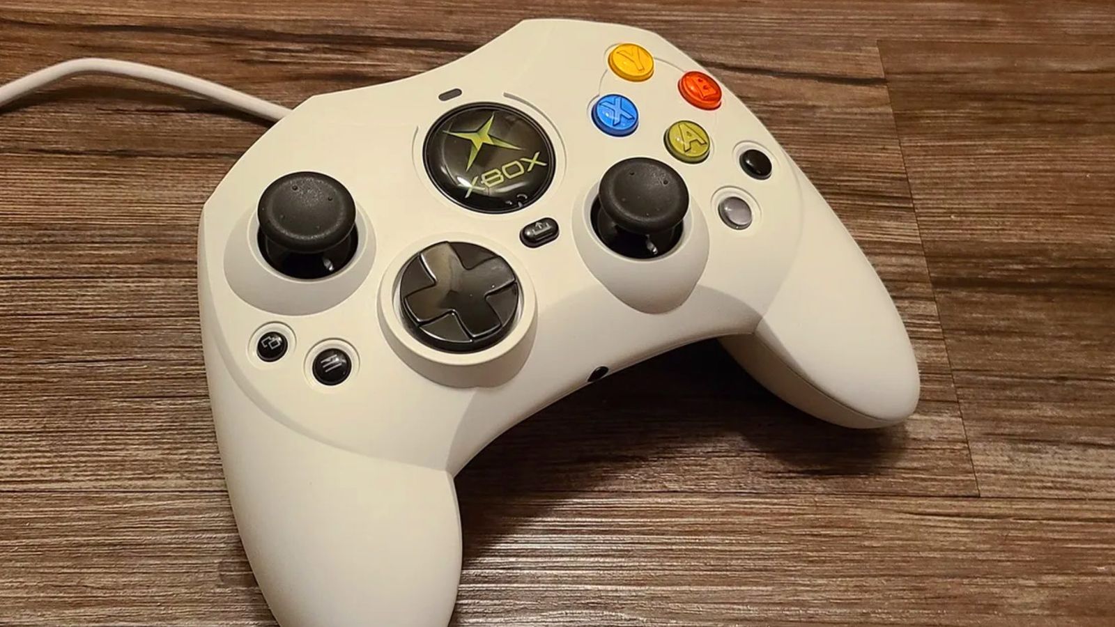 The Hyperkin Duchess Original Xbox S controller in a white skin on a wooden table 