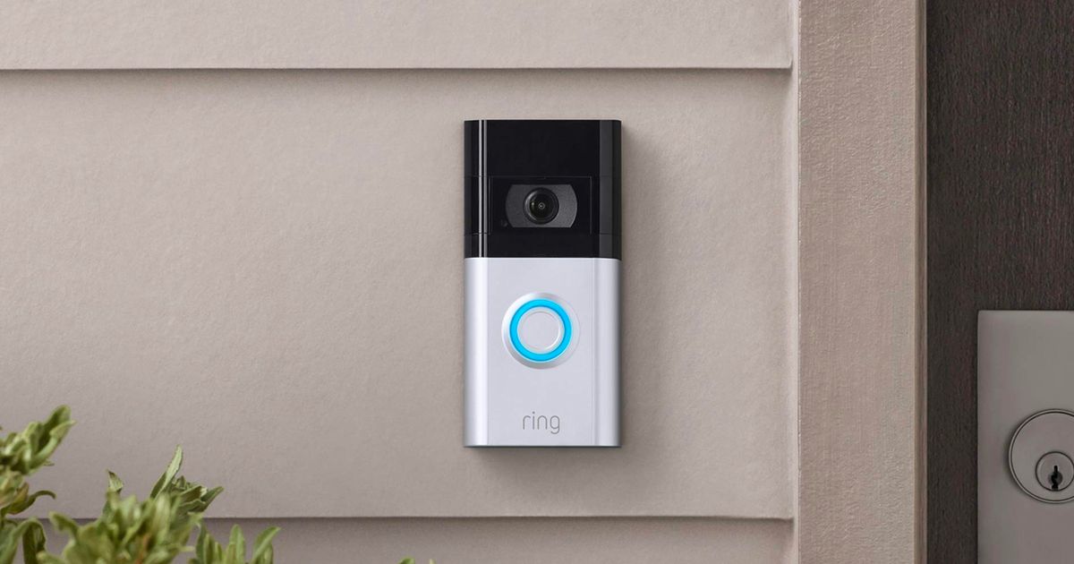 A silver and black Ring doorbell with a blue light around the centre button.