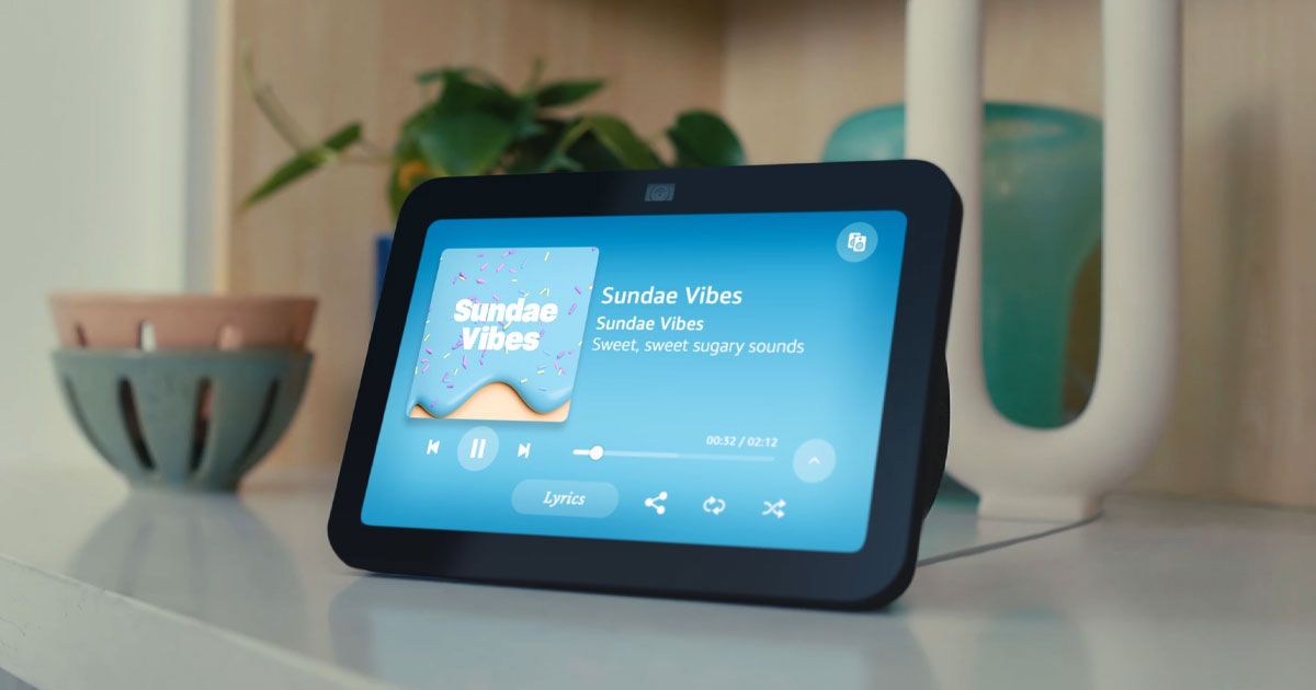 A black Amazon Echo 8 on a wide table top with "Sunset Vibes" song playing on the display.