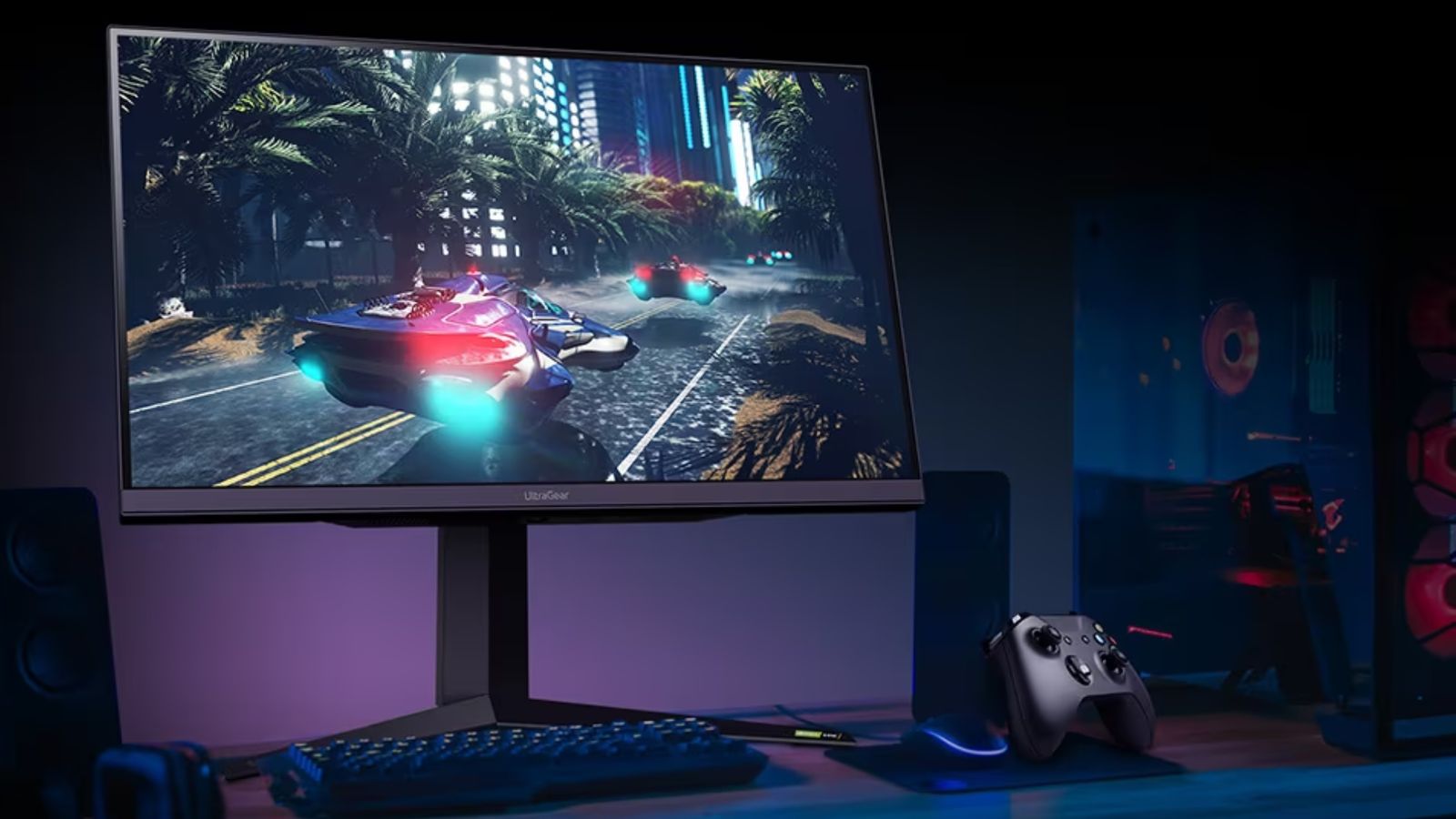 Image of a black LG monitor with hover cars on the display sat on a desk with a black keyboard and controller.