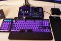 A GoXLR audio mixer sits above a gaming keyboard with the same purple and blue lighting theme