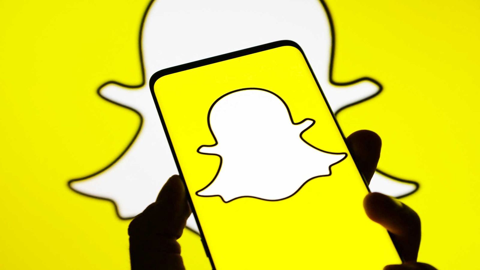Picture of the Snapchat logo as background with a phone showcasing the Snapchat app