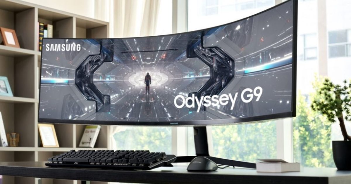 Image of an ultrawide, black Samsung monitor featuring a Sci-Fi scene on the display sat at a desk.