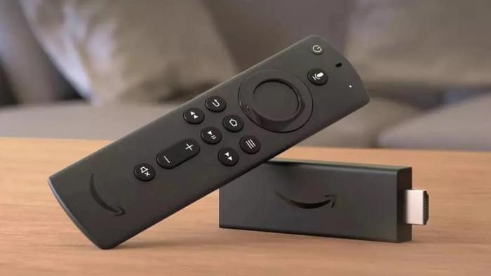 Image of a black Amazon Fire Stick with a black remote control leaning against it.