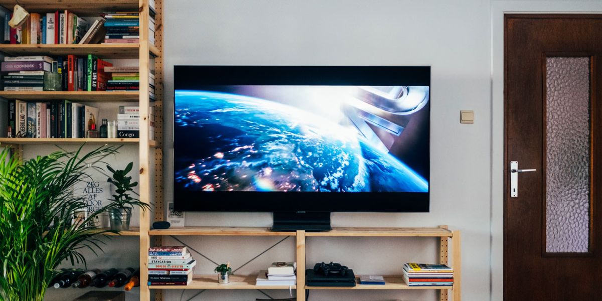 Image of a black flatscreen TV on brown wooden book shelf in living room.