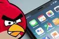 Angry Birds’ Red next to an iPhone 12 Home Screen resting on a table 