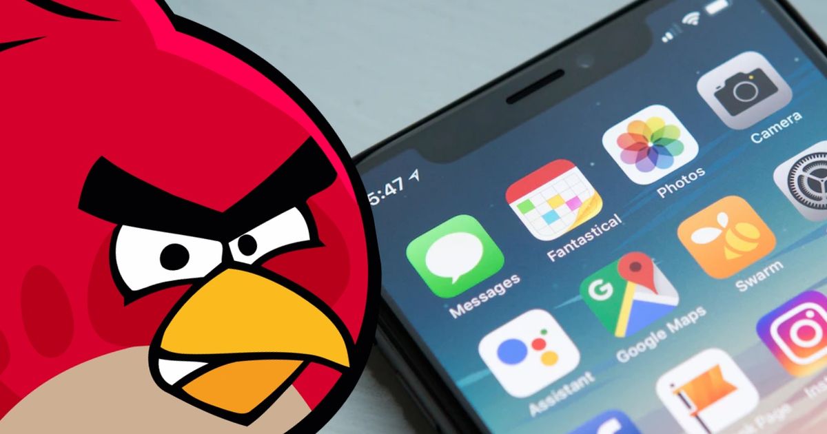 Angry Birds’ Red next to an iPhone 12 Home Screen resting on a table 