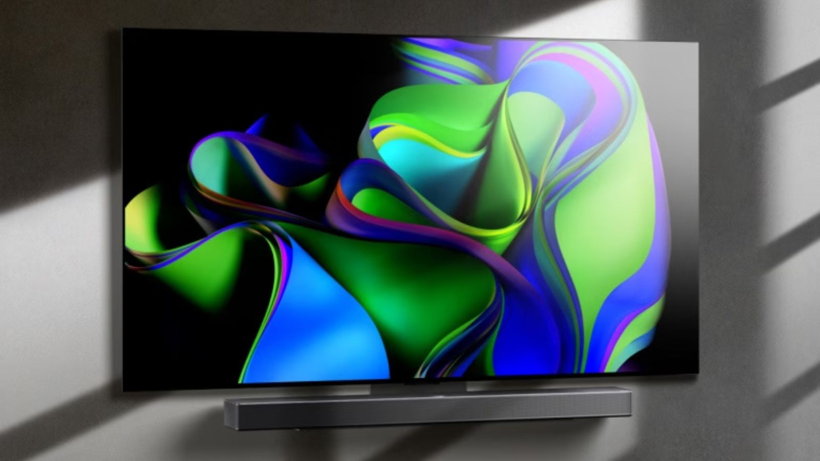LG C3 TV mounted onto a grey wall featuring a green and blue pattern on the display.