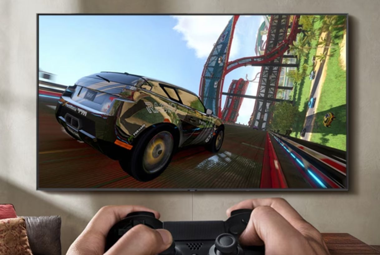 Image of someone holding a black controller playing a racing game on a flatscreen TV.