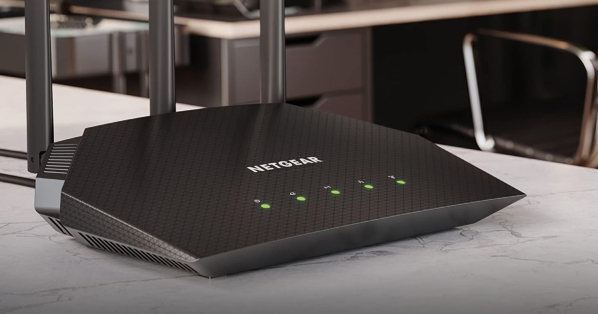 A black WiFi router with five green lights on the front and three antennae coming out the back.