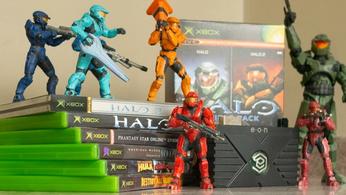 An EON Gaming XBHD adapter amongst myriad stacks of original Xbox games and Red vs Blue statues