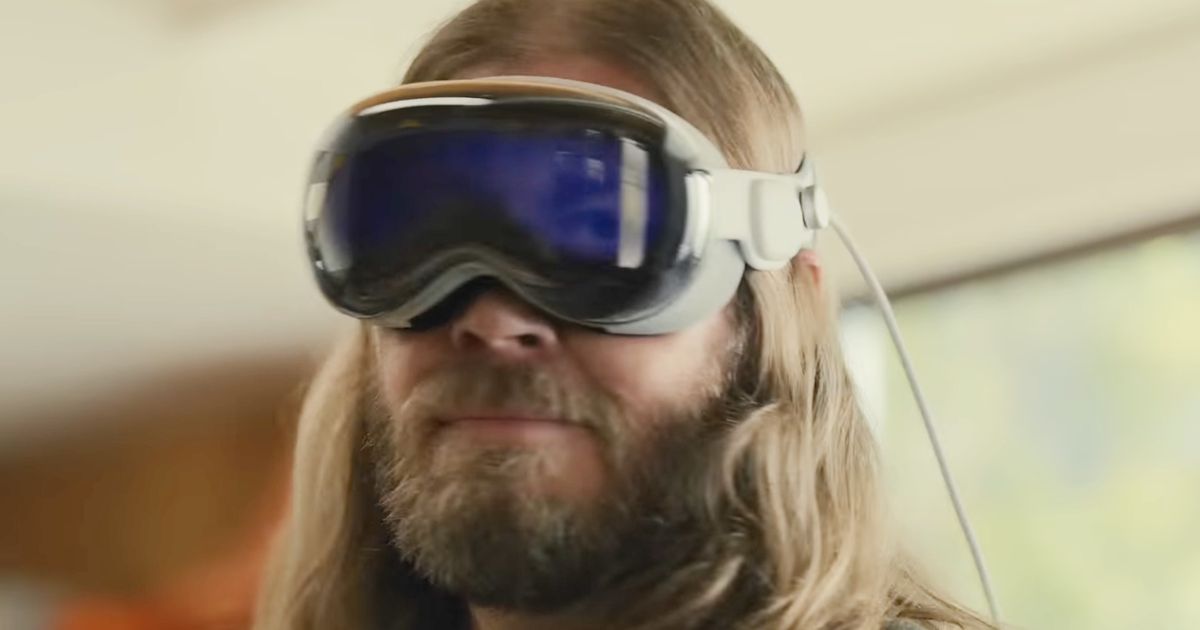 A long haired, bearded man wearing the Apple Vision Pro headset 