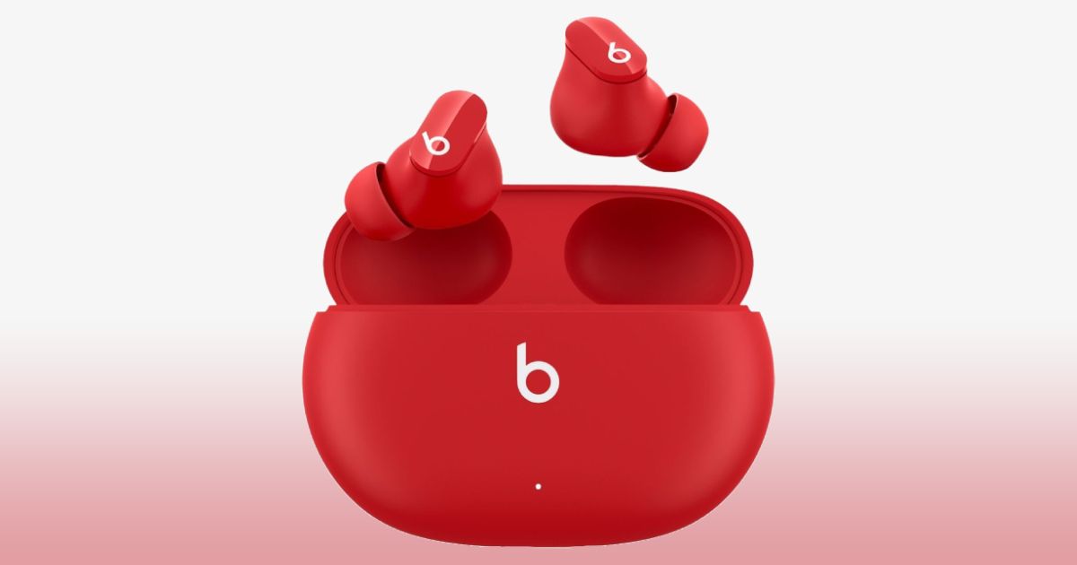 A red charging case with the white Beats logo in the center and two earbuds of the same color coming out of it.