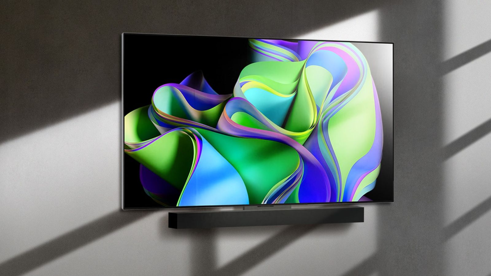 Flatscreen LG TV featuring a green and blue pattern on the display mounted to a grey wall.