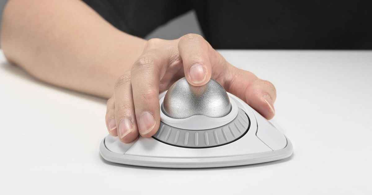 Someone using a white and silver trackball mouse sat on a white desk.