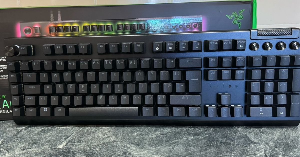 Razer BlackWidow V4 Pro in front of its box and on a marble countertop