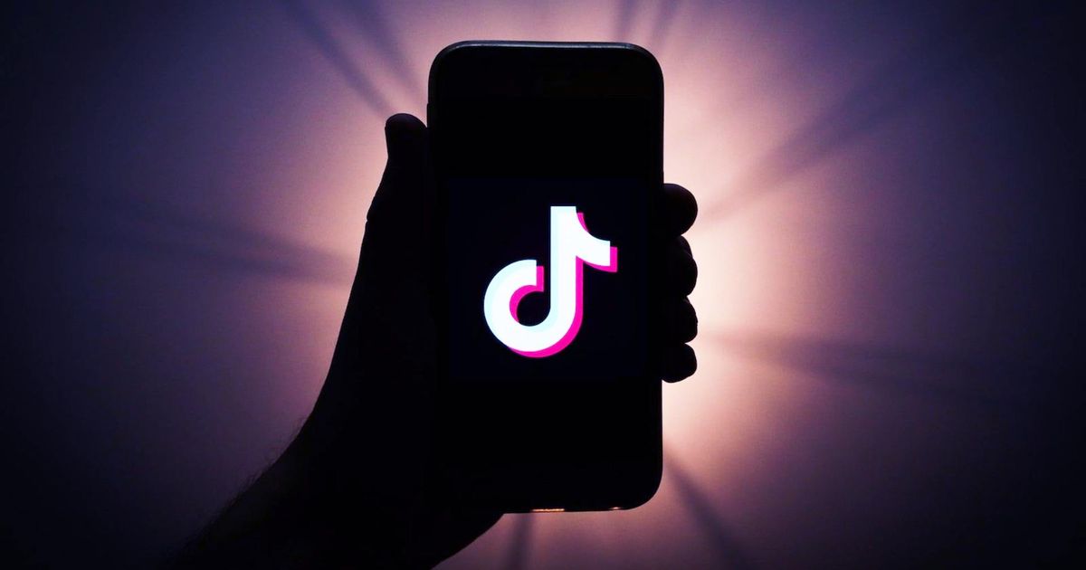 TikTok Wrapped 2023 - picture of a silhoutte of a hand holding a smartphone with TikTok logo