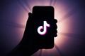 TikTok Wrapped 2023 - picture of a silhoutte of a hand holding a smartphone with TikTok logo