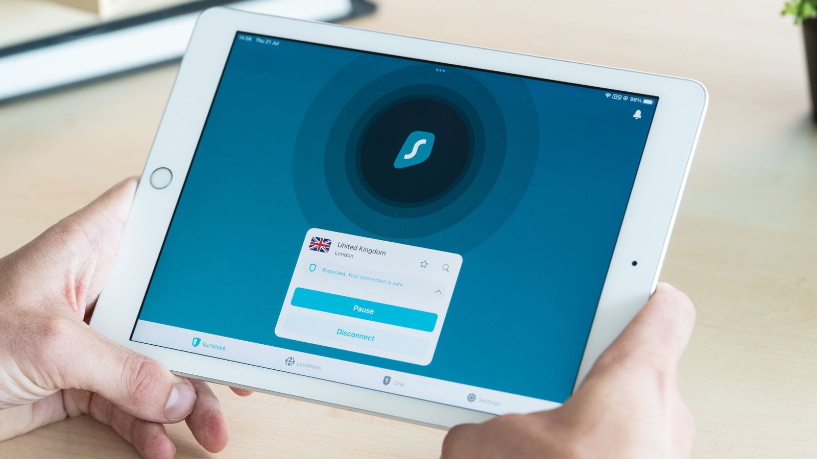 Surfshark VPN is on a white Android tablet, held by two hands