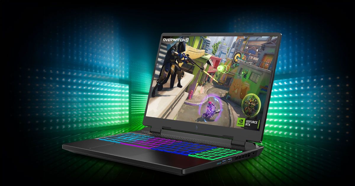A black gaming laptop with Overwatch gameplay on the screen and multicoloured backlit keys in a room surrounded by light blue and green lights.