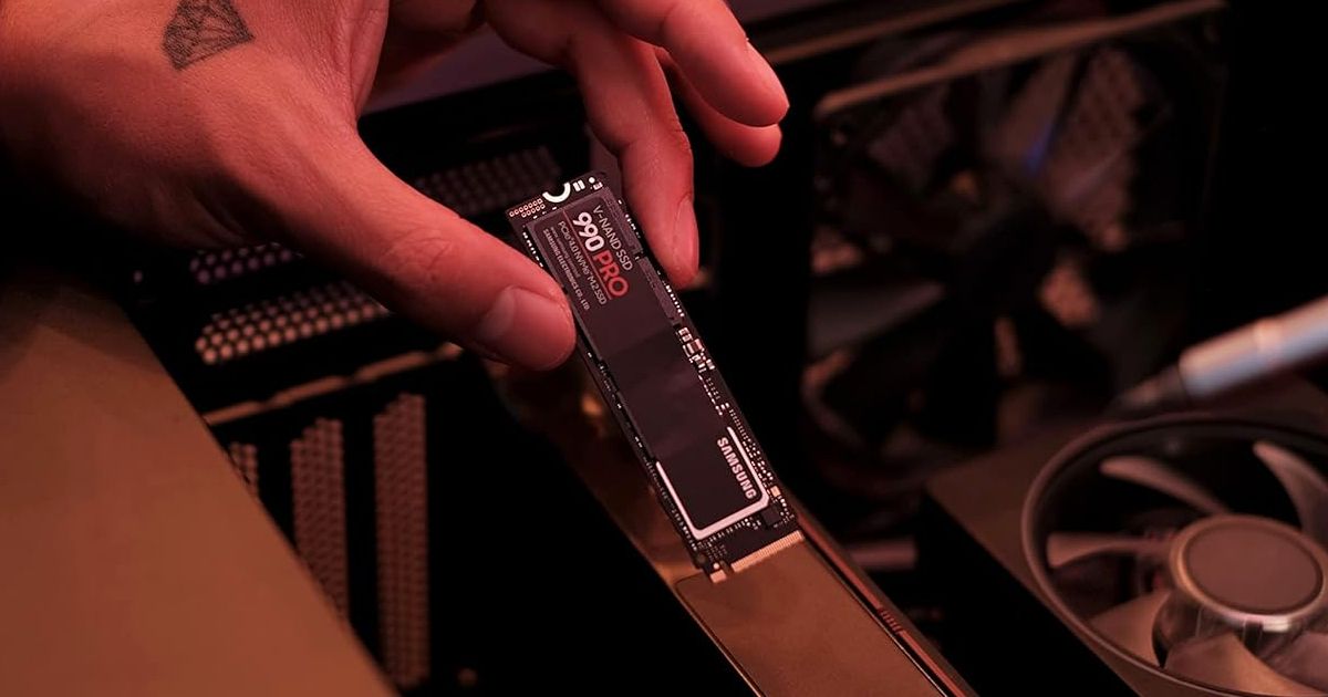 Someone holding a black rectangular SSD featuring white and red branding on top.