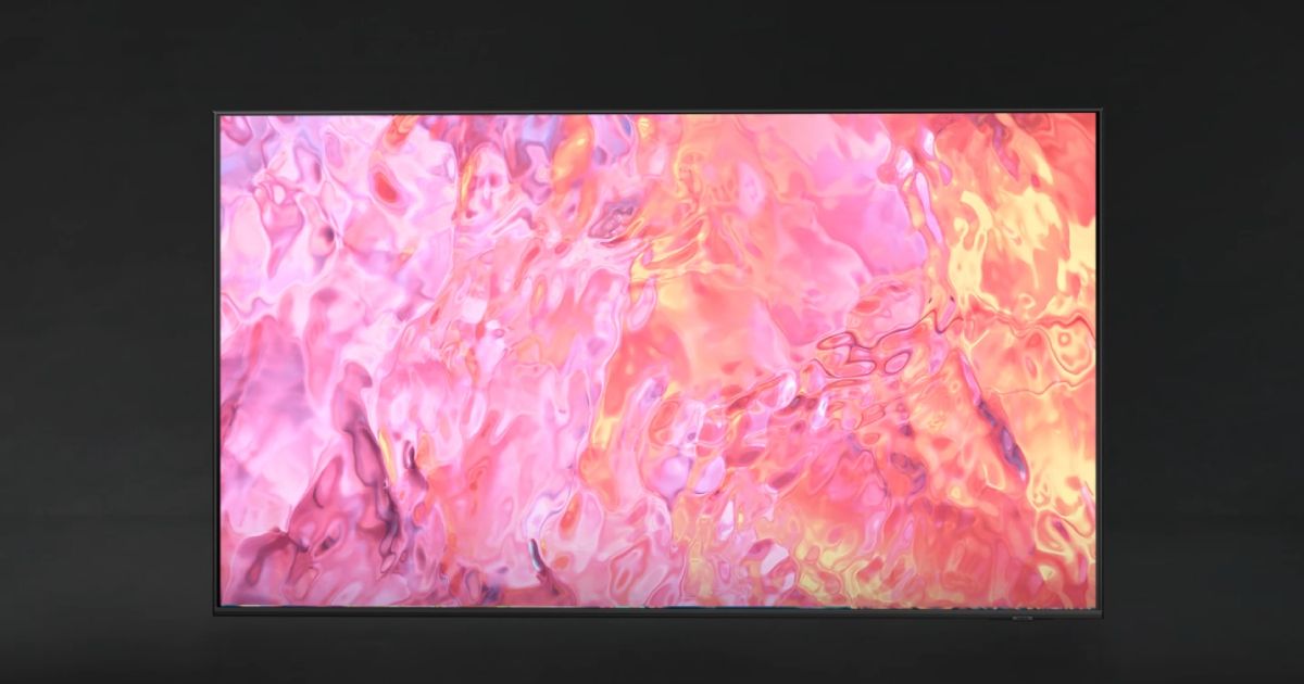 A near-frameless TV in a dark room with a pink pattern on the display.