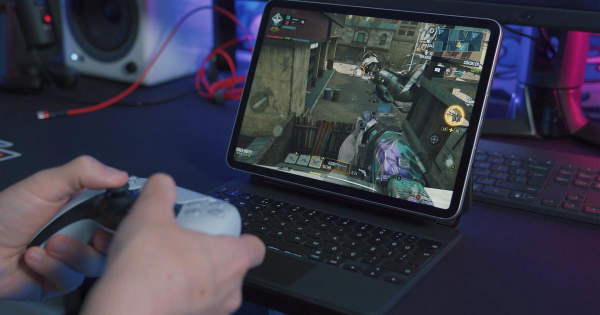 Someone using a white DualSense controller with a tablet.