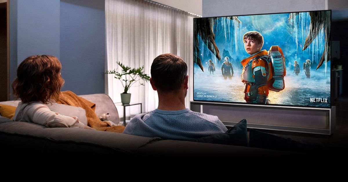 Image of two people sitting on a sofa in front of an LG TV with a Netflix advert on the display featuring a kid in an orange space suit.